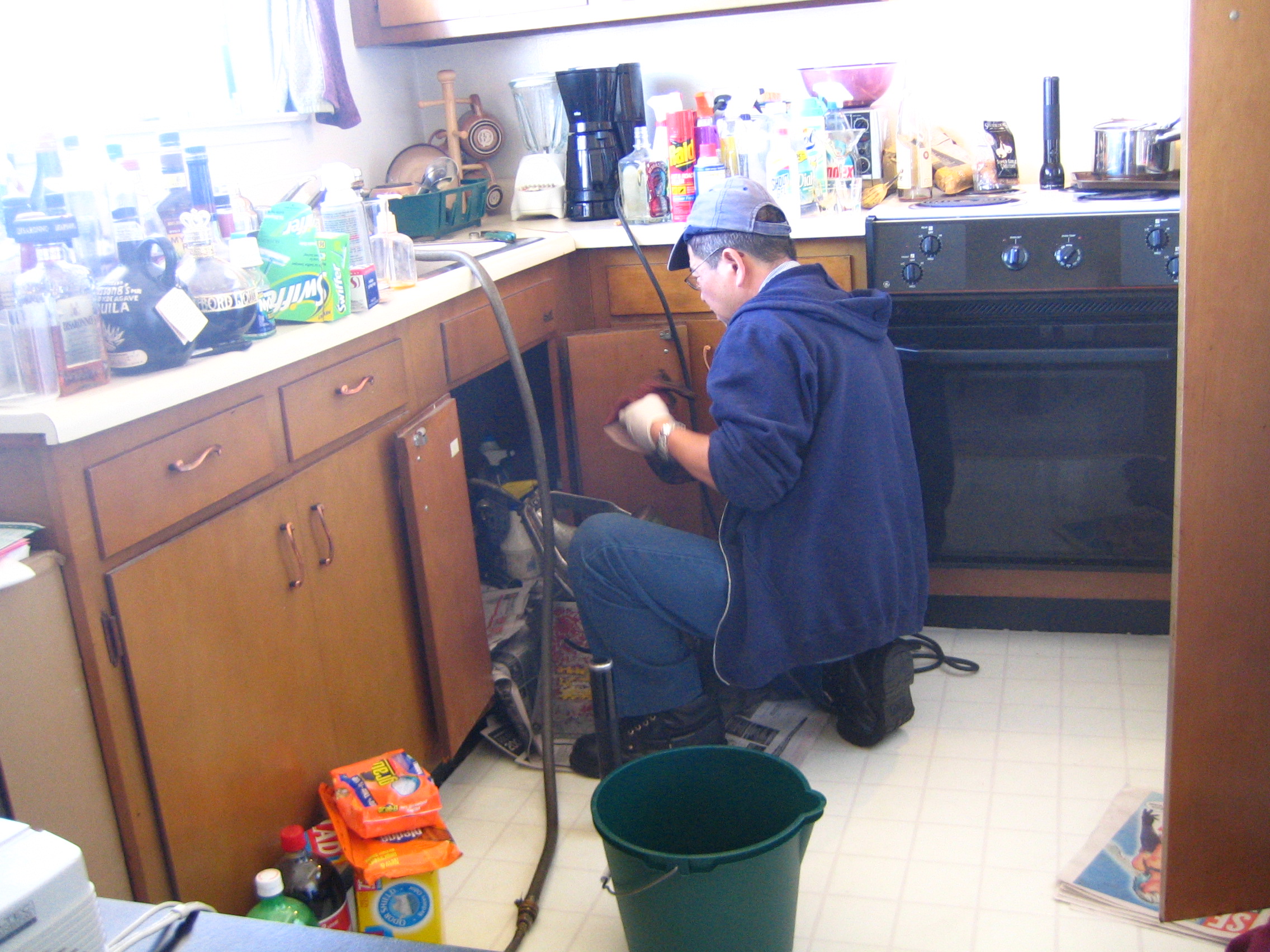 Plumber repairing pipes under a kitchen sink
